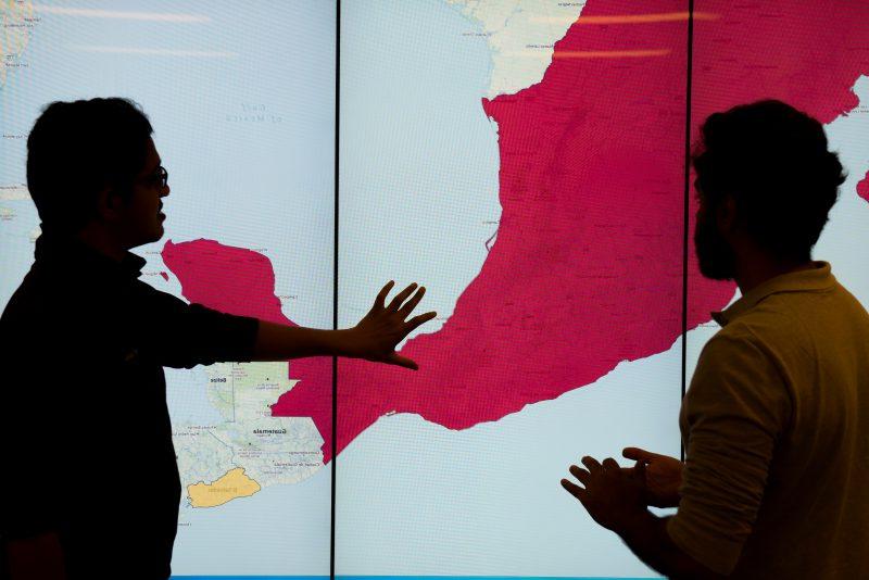 Graduate students in the Discovery Analytics Center with displays from the EMBERS Project at Virginia Tech's Arlington Research Center. EMBERS is a system for forecasting societal significant societal events from open source surrogates.